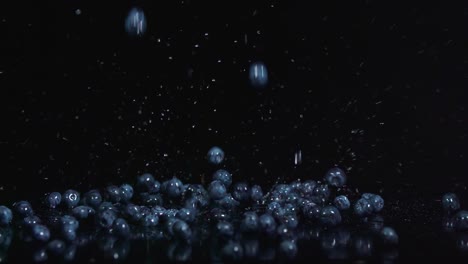 blueberries falling into a pile on black surface with splash