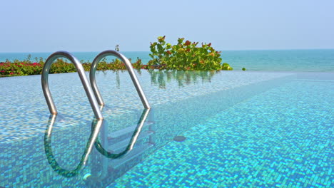 entrada de la piscina infinita frente al mar con pasamanos de metal