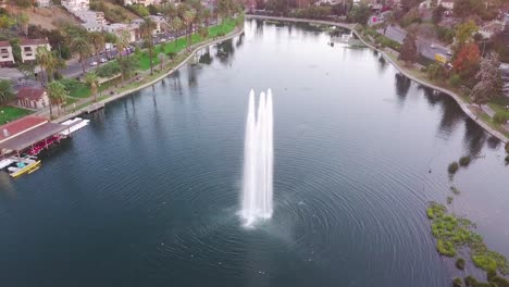 la: drone shot of echo park lake and fountain with downtown skyscrapers in the distance at sunset