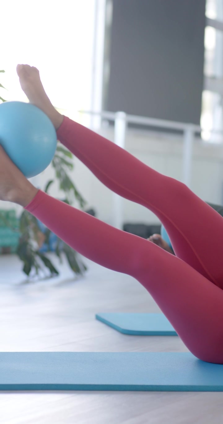 Video verticale: Due donne sui tappetini che iniziano a passare dal plank sugli avambracci al plank laterale con una palla blu per il core.