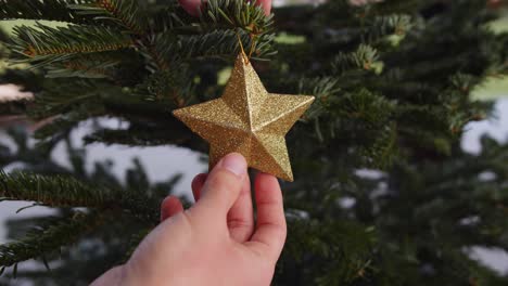 colgando estrella dorada en el árbol de navidad verde de cerca 4k