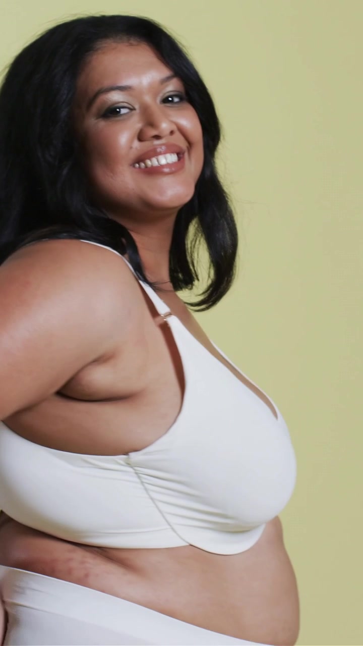Video verticale: Modella in posa che si gira e si sistema i capelli sul set, con la telecamera accesa, mostrando reggiseno e slip bianchi.