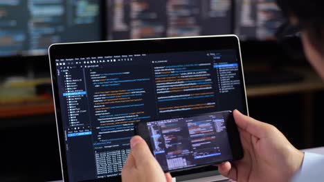 programador trabajando en código en portátil y teléfono inteligente