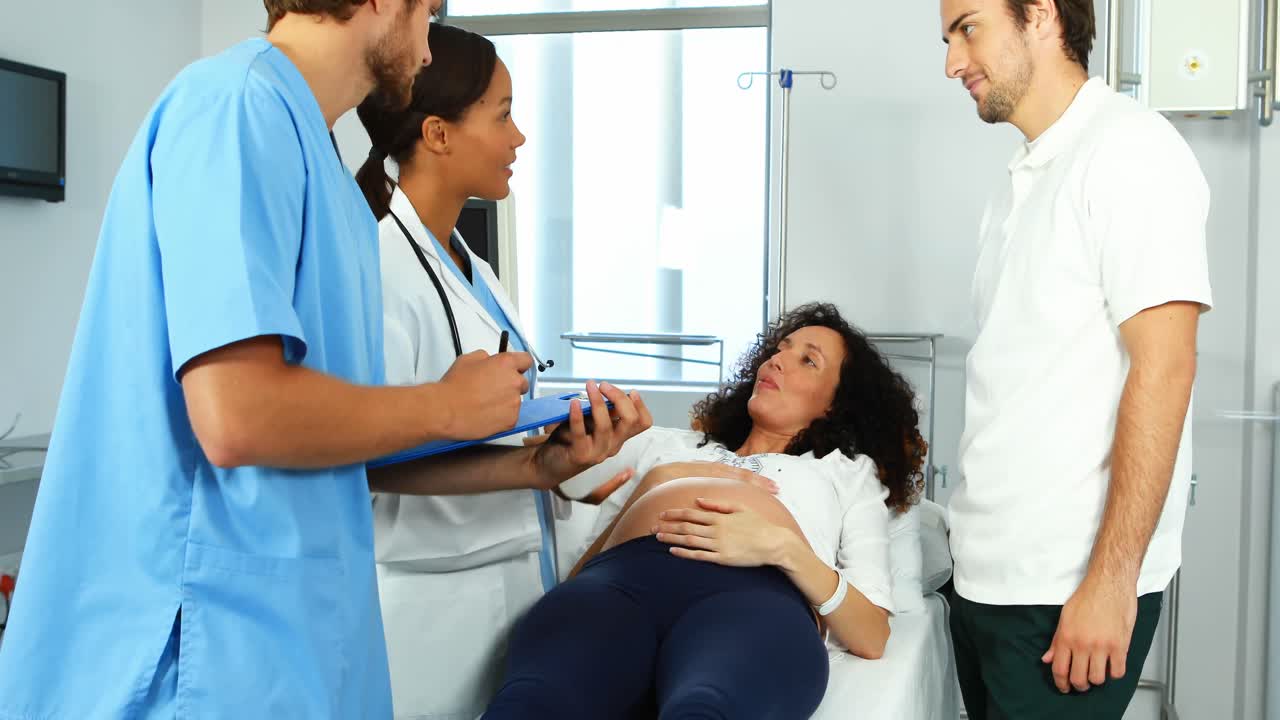 Doctor talking to pregnant woman in ward