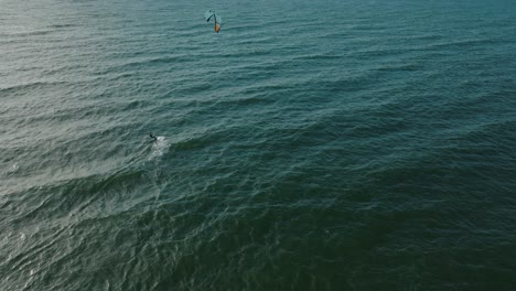 establishing aerial view of a group of people engaged in kitesurfing, sunny summer day, high waves, extreme sport, baltic sea karosta beach , wide birdseye drone shot moving forward