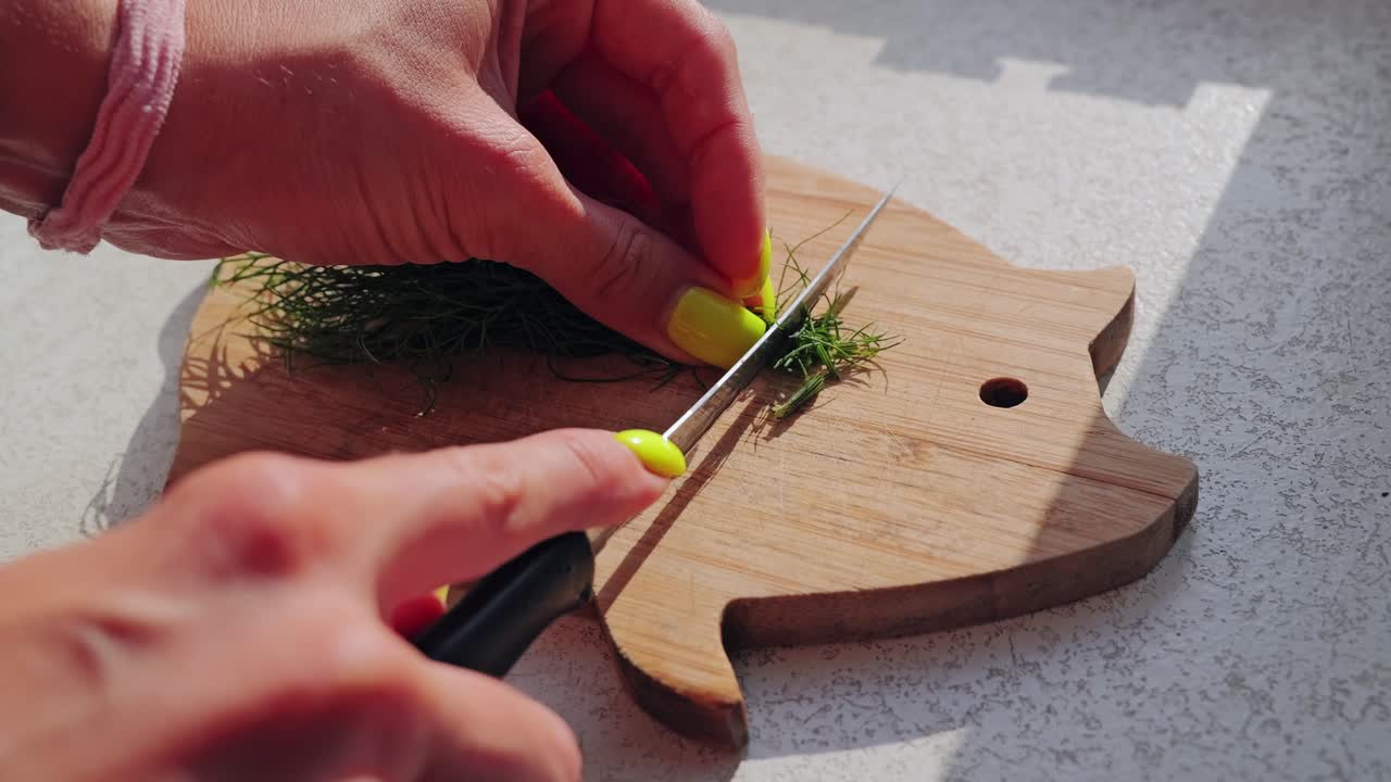 Slow motion close up female hands chopping dill herbs on pig shaped board