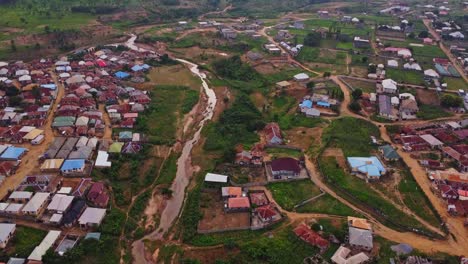 stunning aerial of slums in the outskirts of abuja, the capital city of nigeria, africa. a dry creek runs through the shanty town