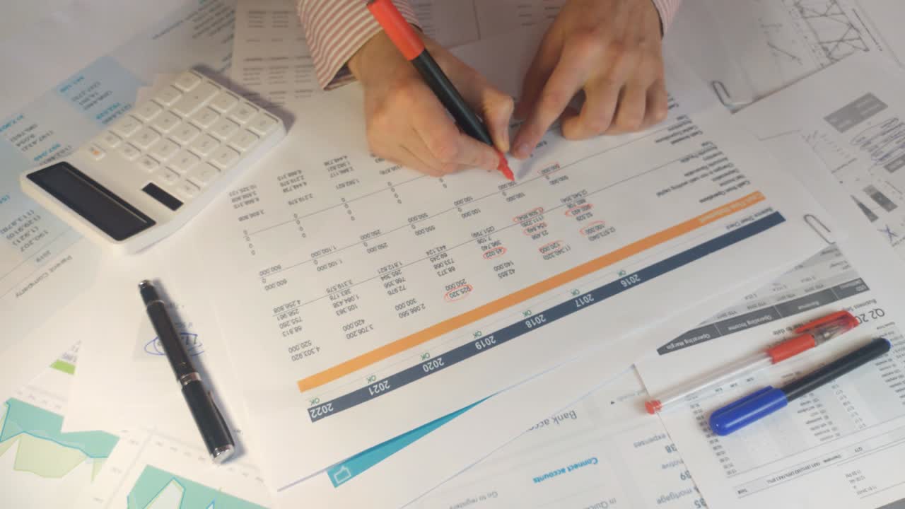 primer plano de un marcador rojo haciendo notas sobre los estados financieros para la auditoría