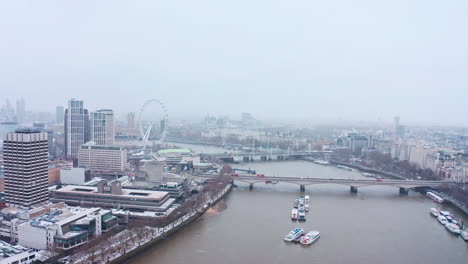 Toma-Aérea-Giratoria-Cinematográfica-De-La-Nieve-Que-Cae-Londres-Puente-De-Waterloo-Banco-Sur-Ojo-De-Londres