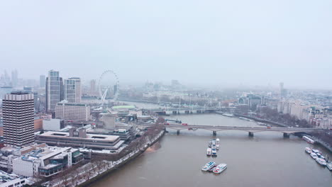 cinematic rotating aerial shot of snow falling london waterloo bridge south bank london eye