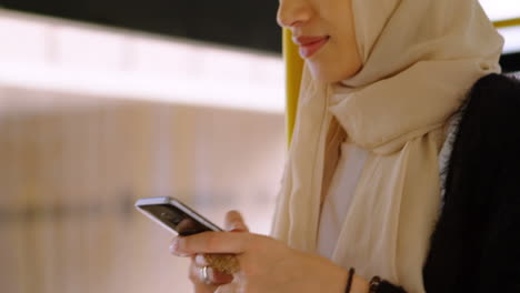 animation of asian woman in hijab using smartphone over cityscape