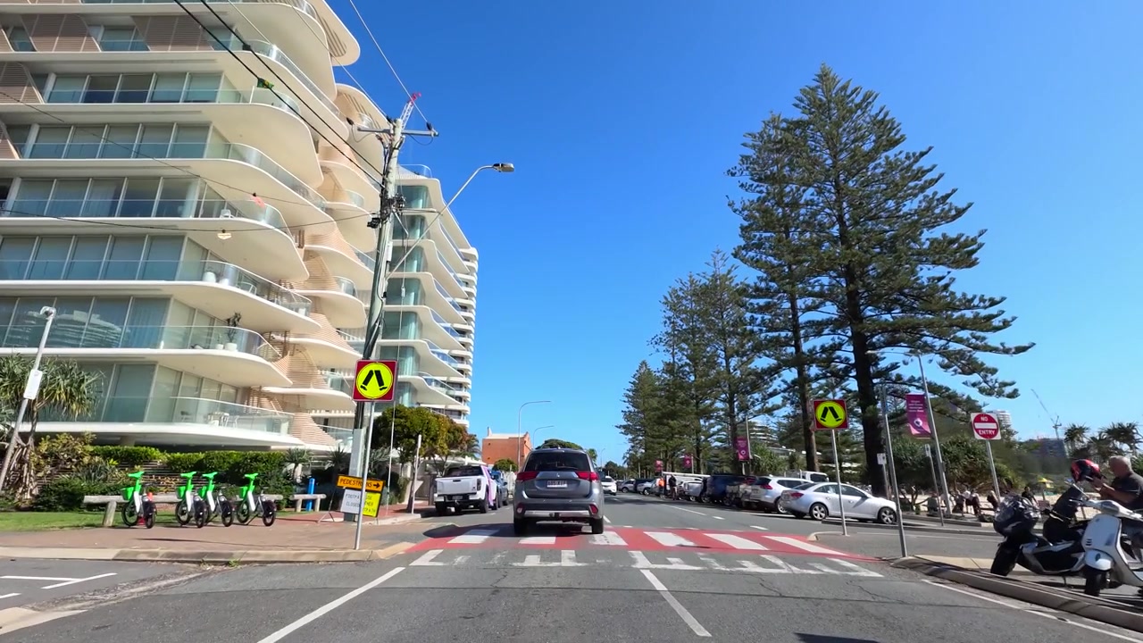 Ripresa di un veicolo in movimento su una strada asfaltata assolata, oltre architettura moderna e auto parcheggiate