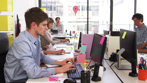 Colleagues-passing-paperwork-across-desk-in-a-busy-office