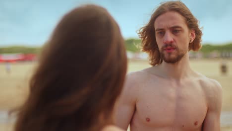the man looks shocked upon seeing a woman who has been abused on the beach - close up