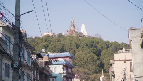 swayambhunath stupa on top of the mountain hill with lush green trees in kathmandu valley, nepal. view from the road. - wide rolling