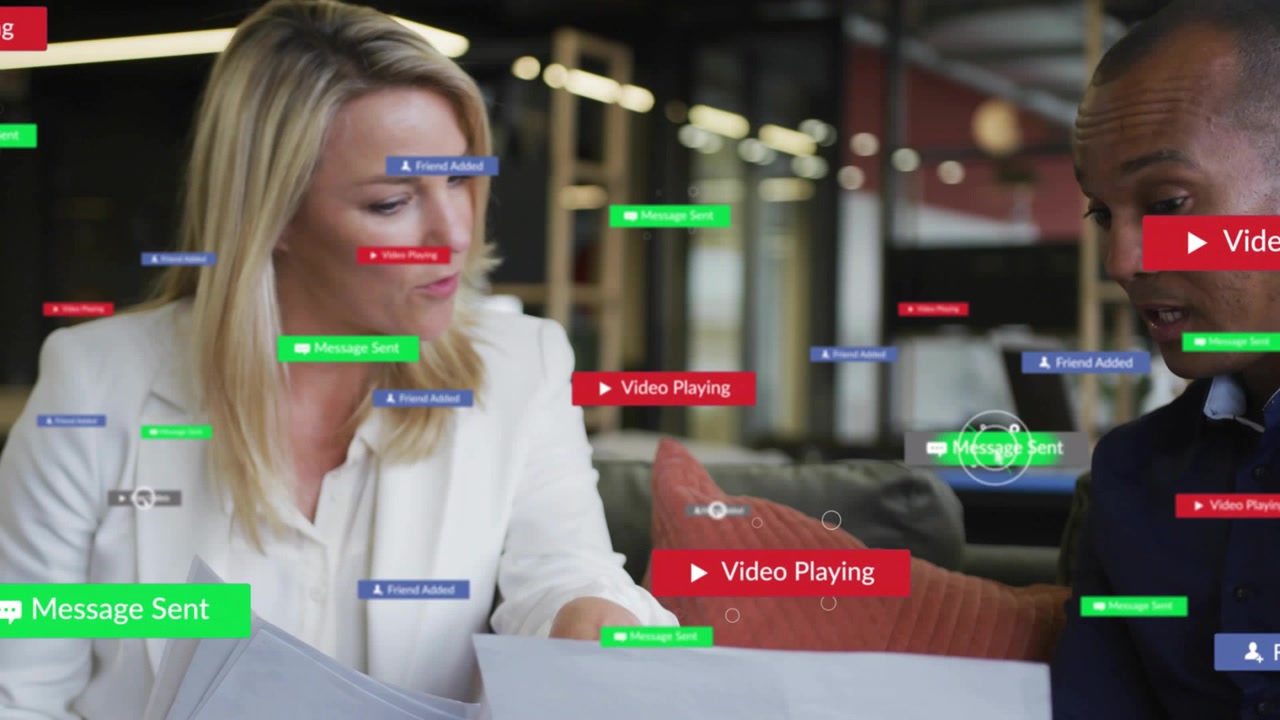 Woman pointing papers and man watching laptop in business, overlays appearing and fading for review
