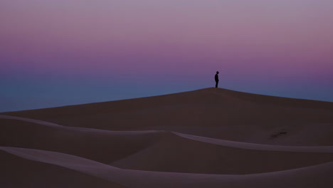 silhouette of a person on a sand dune at sunset