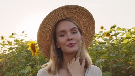 Frau-Mit-Hut-In-Einem-Feld-Von-Sonnenblumen-In-Die-Kamera-Posieren