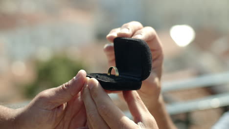 primer plano de manos abriendo caja con anillo de compromiso