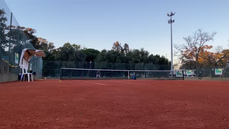 Man-athlete-doing-a-great-serve-during-an-outdoor-tennis-game-on-the-orange-clay-tennis-court-in-Monsanto,-Lisbon