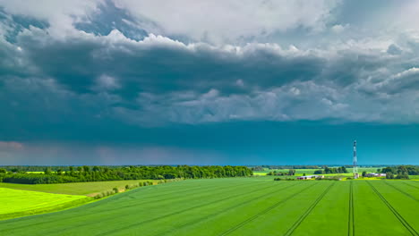 Dramatic-cloudburst-storm-over-countryside-fields-of-grain---aerial-hyper-lapse