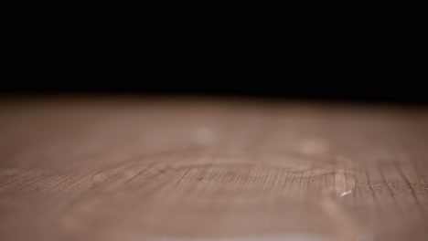 super slow motion water drops falling on a wooden surface, creating ripples