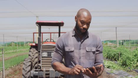 Video-of-african-american-man-standing-with-tablet-in-front-of-tractor