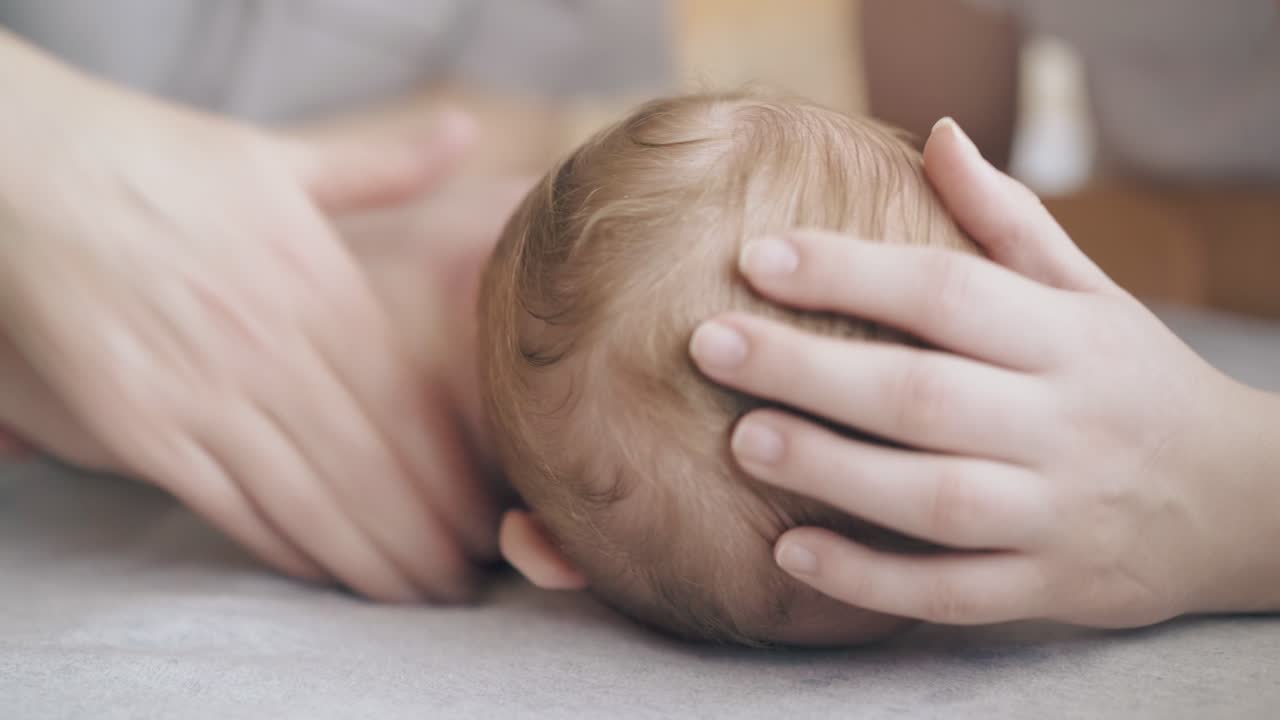 짧은 머리카락을 가진 유아 소년은 바뀌는 테이블에 배에 누워 있습니다.