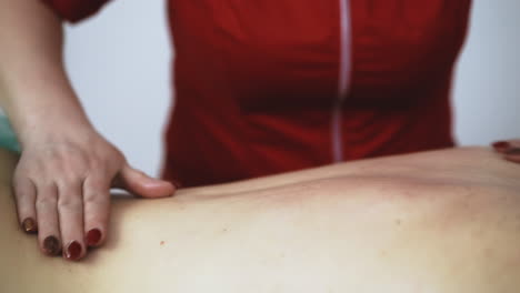 el terapeuta de rojo hace un procedimiento de masaje clásico al paciente.
