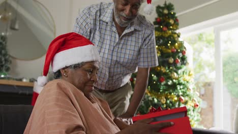 Animation-of-happy-african-american-senior-couple-sharing-with-presents-at-christmas-time