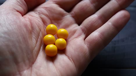 yellow dragees from jar in hand