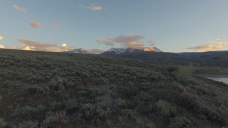 Hermosa-Puesta-De-Sol-Volar-Sobre-La-Ladera-De-La-Montaña-En-Las-Montañas-Rocosas-Cubiertas-De-Nieve-Y-El-Lago