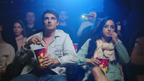 una pareja joven comiendo palomitas de maíz en el cine.