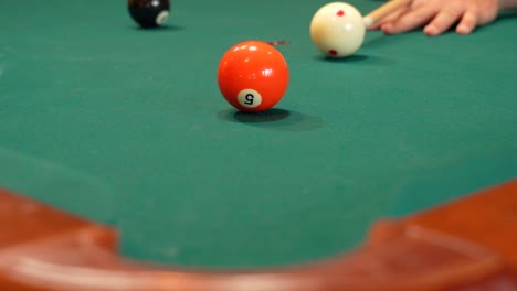 Closeup-of-Person-Playing-Pool-Addressing-and-Shooting-Orange-Solid-5-Ball-into-Corner-Pocket-after-Practice-Strokes-using-Cue-Ball,-Open-Bridge-Hand-with-Wooden-Cue-Stick-and-Green-Felt-or-Cloth