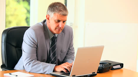 middleaged man in suit working on a laptop