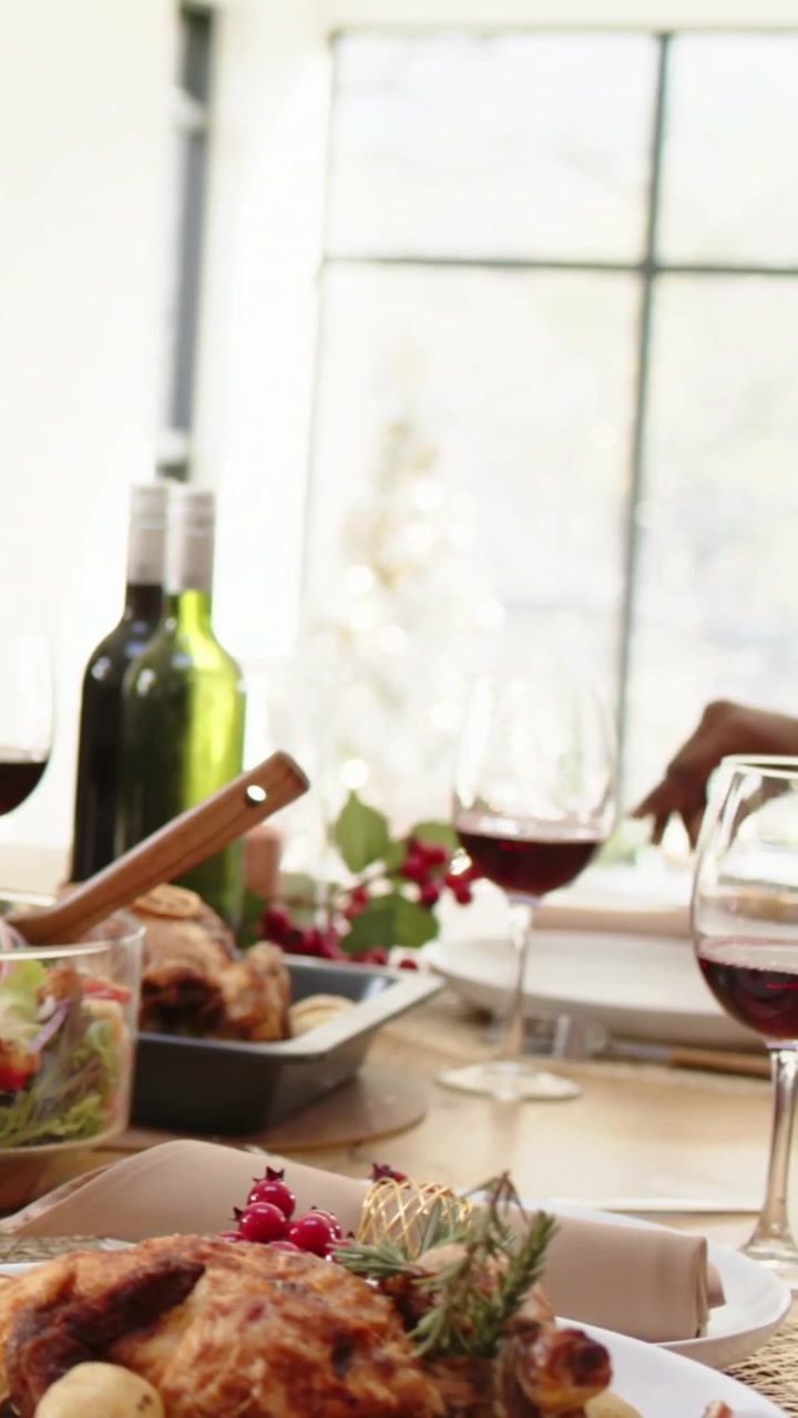 Vertical video: Camera panning at home, red sweater passing vegetables for family meal around roast