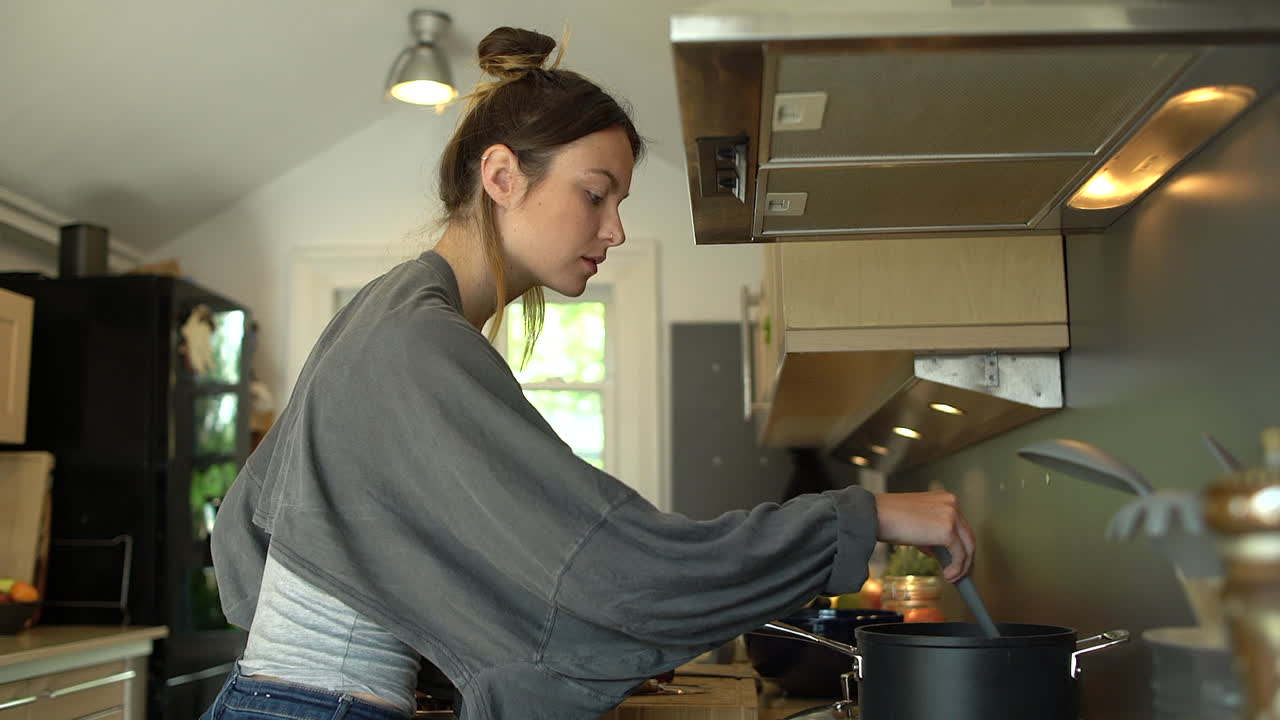 Young Woman Cooking and Stirring Pot Contents