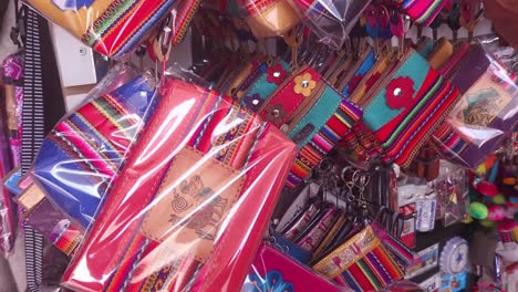un puesto de mercado lleno de muchas carteras de monedas coloridas con muchos patrones en el estilo de la ropa y tapicería de los andes