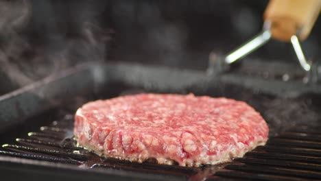 raw burger meat is fried with hot steam in a frying pan.