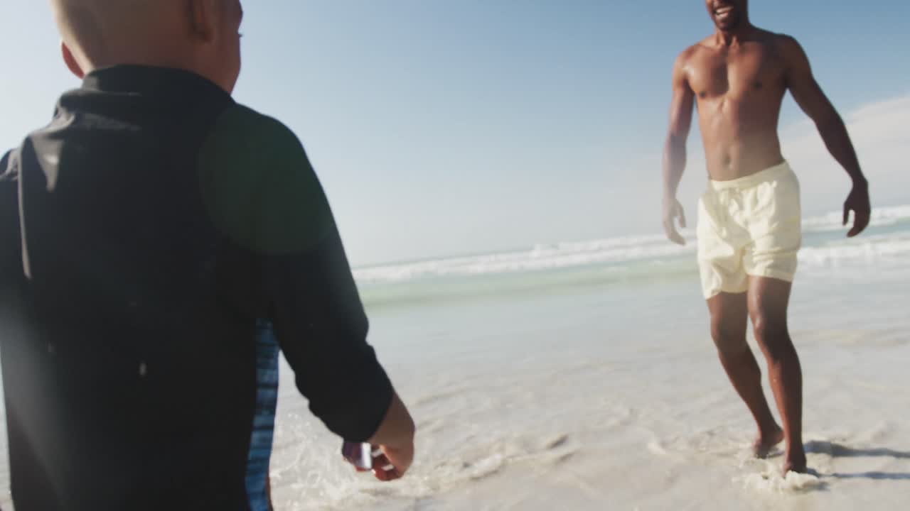 아프리카계 미국인 가족 이 해변 의 파도 근처 에서 함께 즐기고 있다