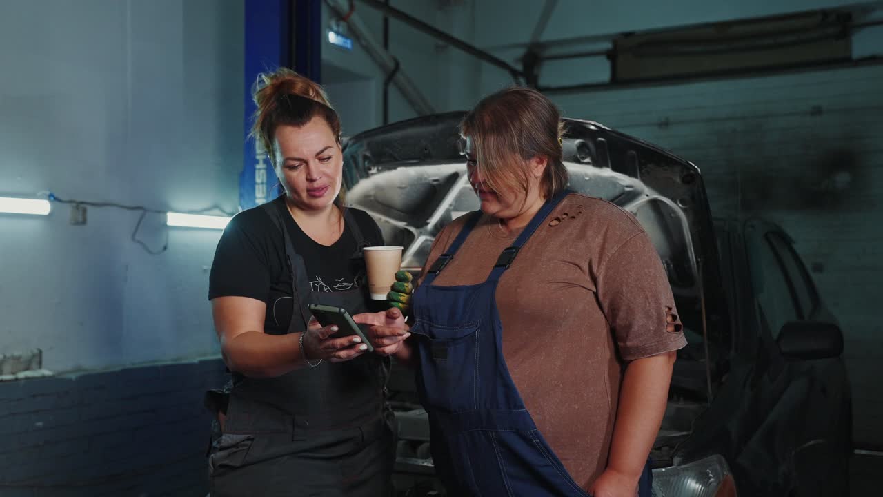 Two Women Mechanics Discussing Car Repair in a Garage