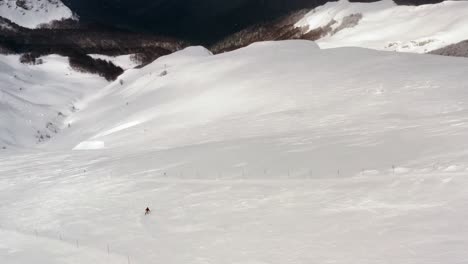 AERIAL---People-skiing-in-mountains-at-Kolasin-ski-resort,-Montenegro,-pan-left