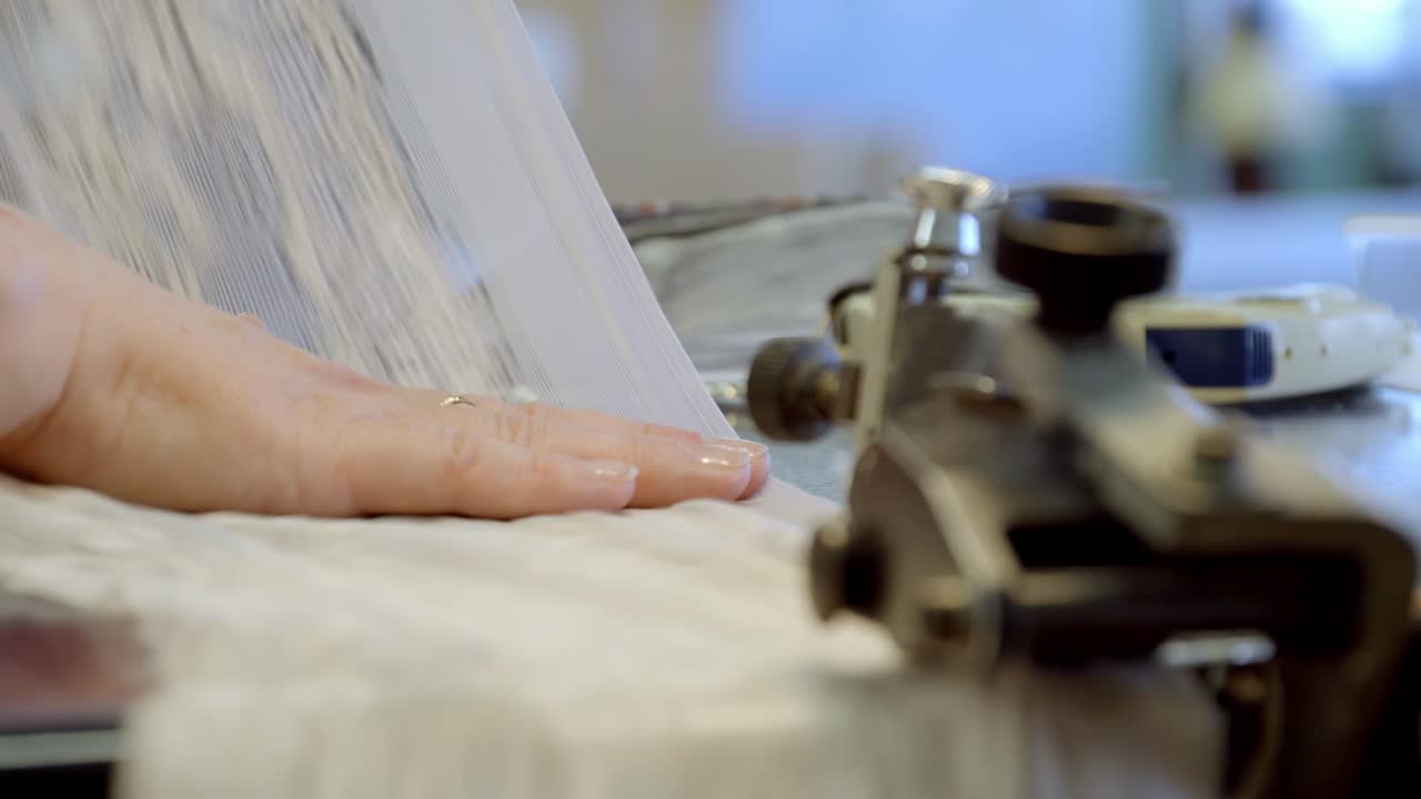 Hand smoothing fabric near sewing machine in a bright workshop
