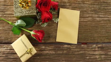 rosas rojas, cajas de regalo y tarjeta en una superficie de madera 4k