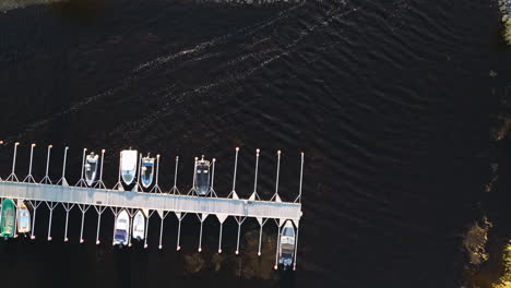 Above-View-Of-Boats-Moored-On-Pier-With-Calm-Water-Lake-In-Sweden-During-Autumn