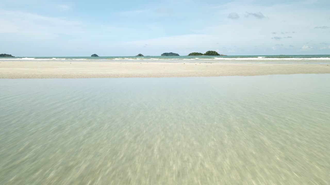 드론 플라이는 하얀 모래 해변에서 바다와 섬을 향해 빠르게 날아갑니다.