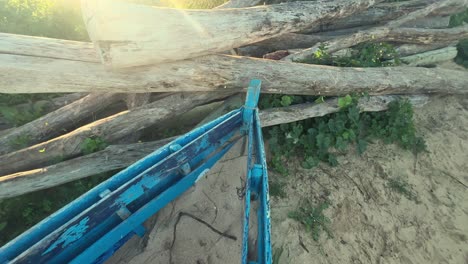 a weathered fishing boat lies in a coastal setting, partially submerged in sand with traces of wooden branches, invoking the charming atmosphere of a fishing village scene