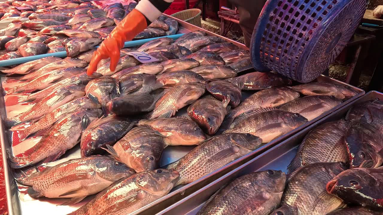 vendedor arreglando pescado en un puesto de mercado ocupado