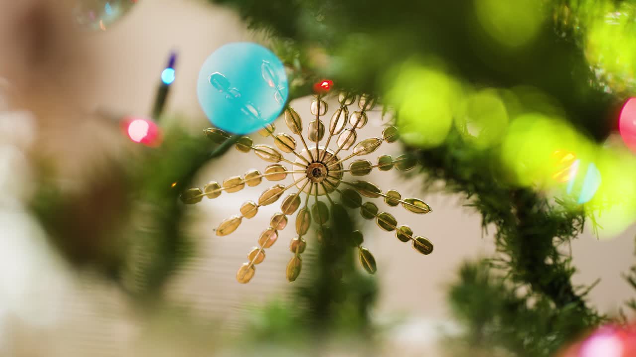 Slow rack from lights to metal star ornament on faux Christmas tree branch.