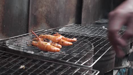 hand putting shrimp on barbecue